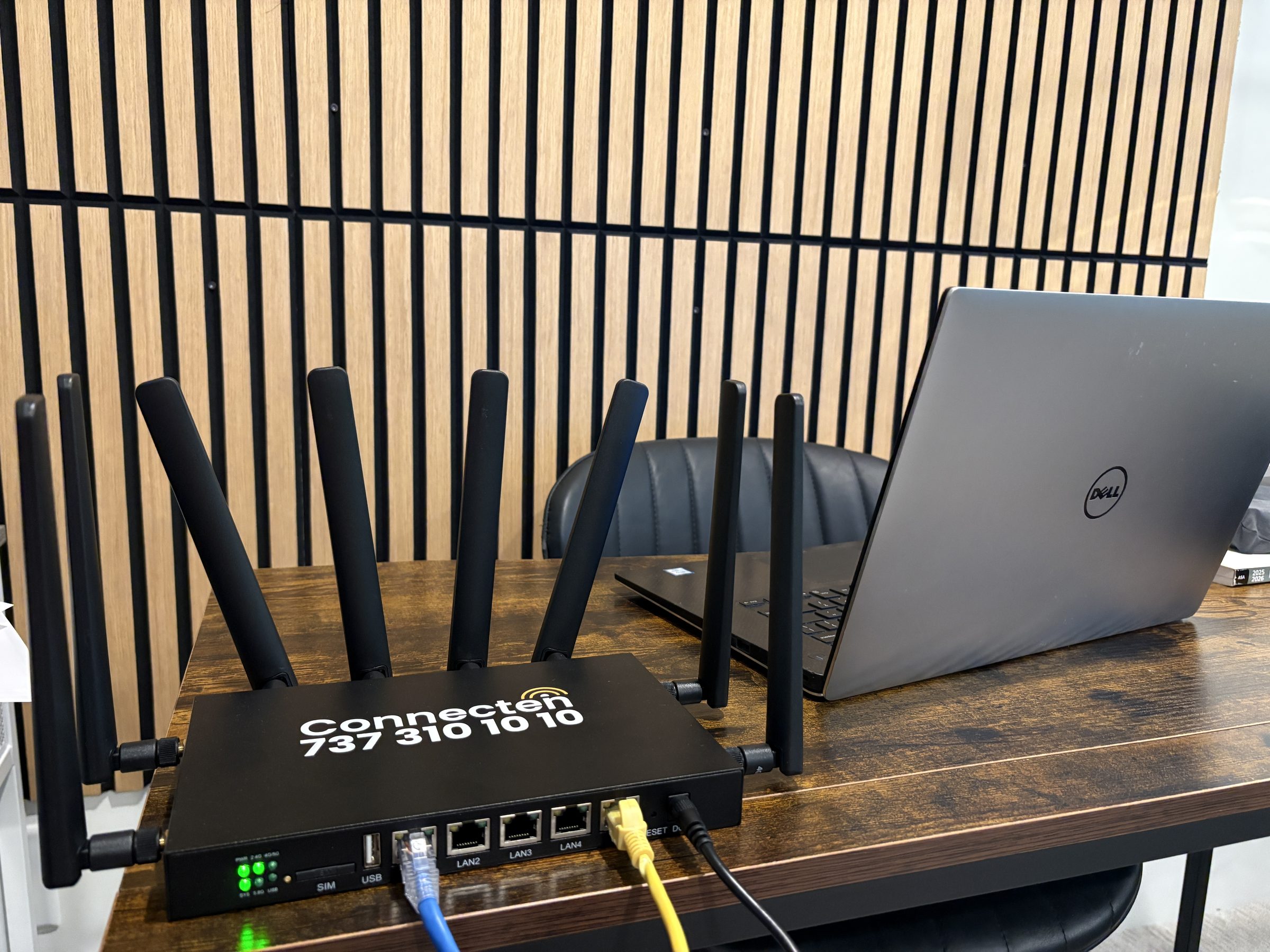 Connecten router on office desk beside a Dell laptop